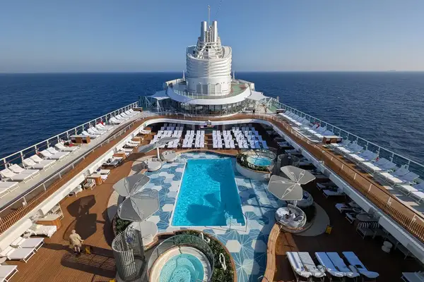 View of a cruise ships pool deck with sun loungers parasols and a clear view of the ocean