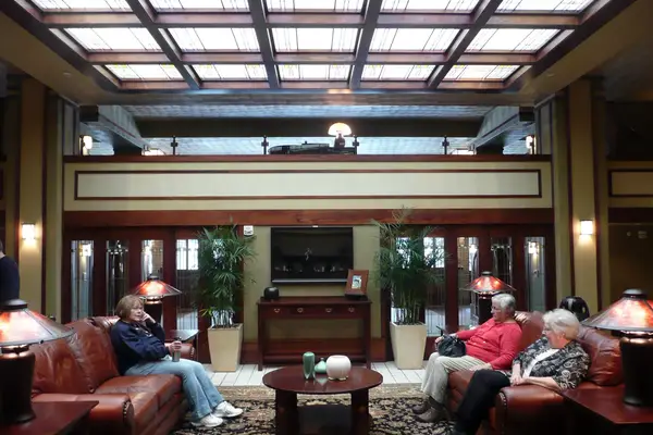 Three mature guests sit in a Frank Lloyd Wright designed hotel in Iowa
