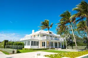 Large upscale house in Palm Beach Florida surrounded by palm trees and landscaped greenery