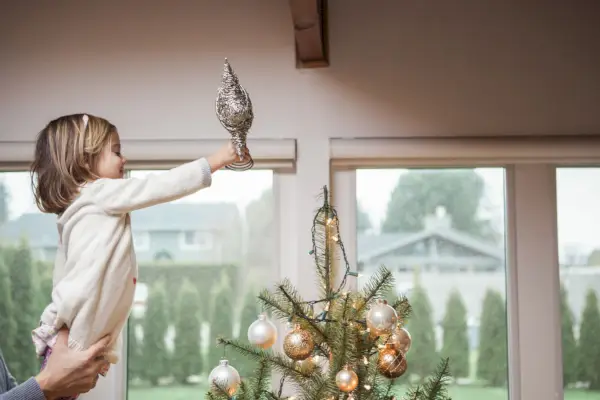 Toddler girl putting star on Christmas tree