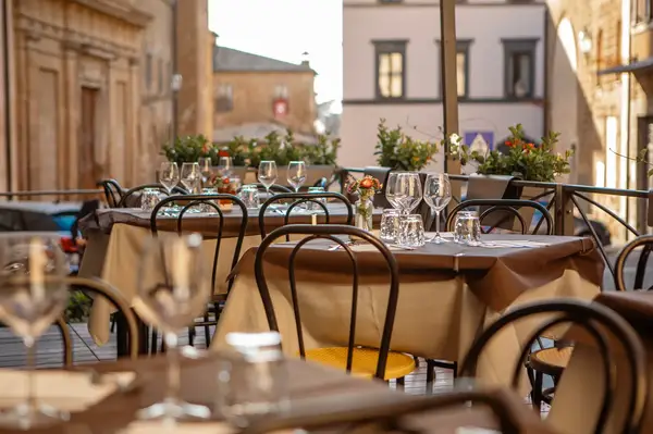 Outdoor dining area with tables set on a terrace in an urban setting surrounded by buildings