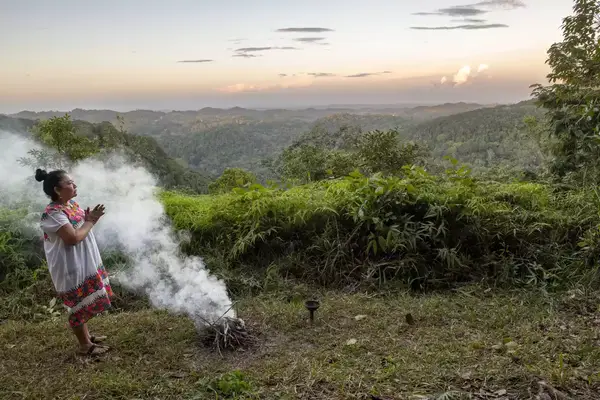 A healer in Belize standing next to a small fire