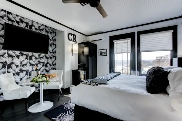 A stylish and modern hotel room with a double bed a small dining table and a wallmounted television