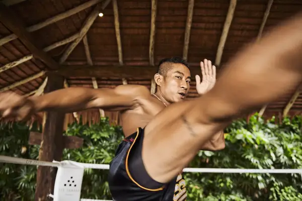 A muay thai boxer performs a kick to the camera