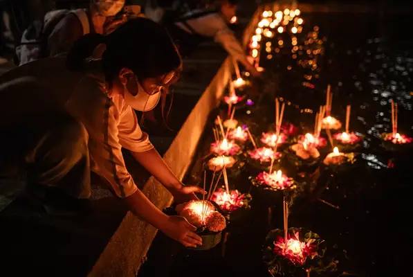 A young girl placing a lantern in the river during Loi Krathong