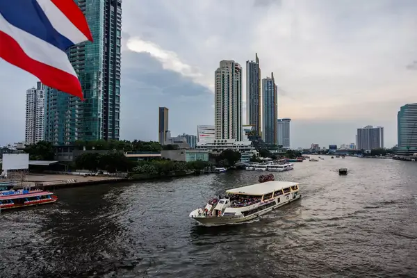 Ferries going down the river past sky scrapers in Bangkok