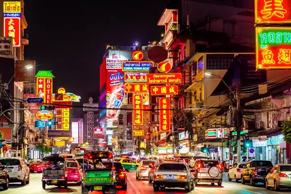 night shot of busy street with bright neon signs in bangkok