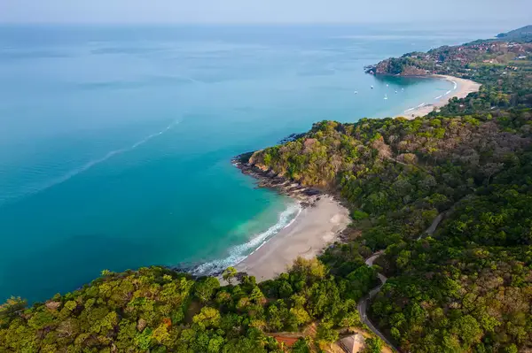 Aerial view of a tropical island with sandy beaches and forested areas beside the coast