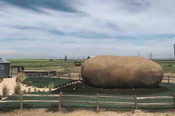 A large potatoshaped structure located in a fenced area in a rural landscape