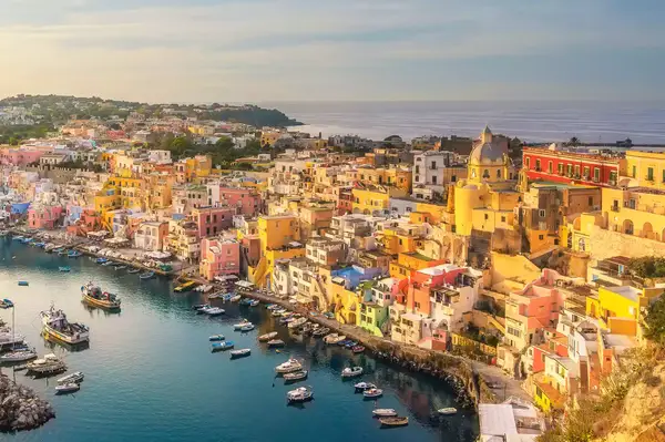 Colorful buildings by a small harbor with boats docked, set in a scenic coastal setting
