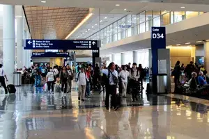 Passengers walking through a terminal at an airport past gates D33 and D34