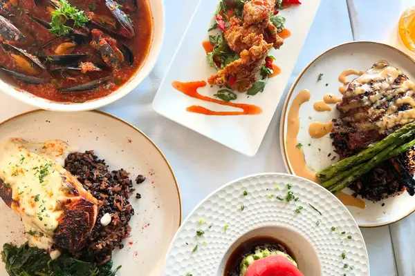 A variety of plated dishes, including seafood, vegetables, and garnishes, arranged on a dining table