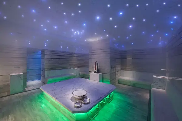 Luxury hammam in the Waldorf Astoria Spa with marble-like surfaces, green lighting, and a starry ceiling