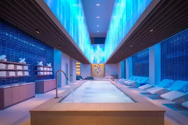 A long pool at Lapis Spa surrounded by lounge chairs and illuminated with blue accent lighting