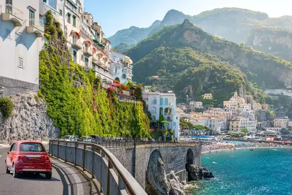 A small red car on a road on the Amalfi Coast