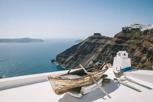 An old canoe on the top of a white building overlooking the ocean on Santorini