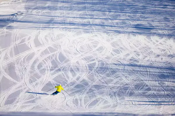 A person skiing down a mountain that has several ski lines