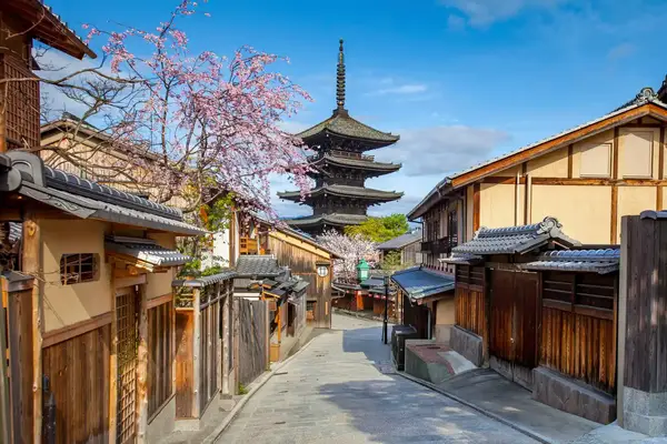 A street in Kyoto with traditional wooden buildings and a pagoda in the background