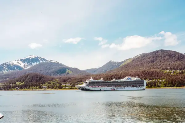 A cruise ship sailing in a calm bay with mountains in the background