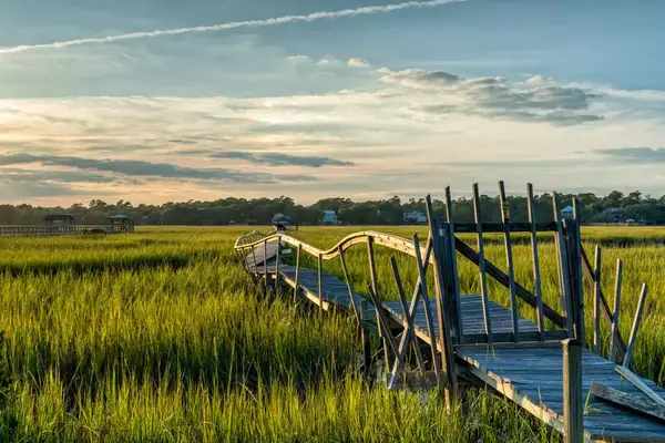 An old dilapidated wooden dock in the marsh grass and inlet of Pawleys Island in South Carolina at sunset
