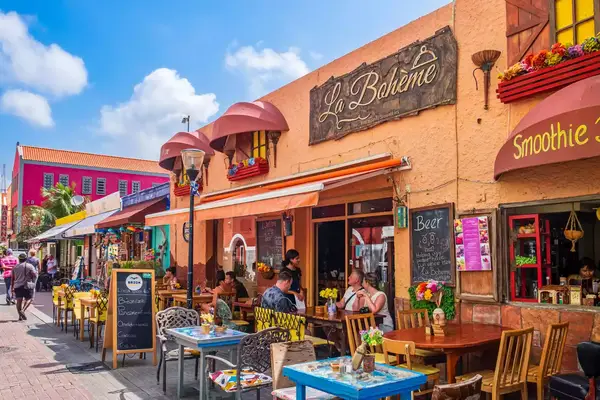 Tourists sitting at the outdoor tables in the pedestrian zone in downtown Willemstad, the capital city of CuraÃ§ao, an island in the southern Caribbean Sea.