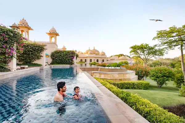 A father and son splash in a villa pool in India