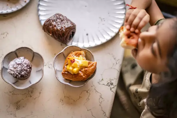 Overhead photo of a child eating pastries.