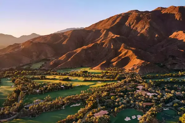 Aerial view of Sensei Porcupine Creek in California with mountains surrounding green, palm tree valley