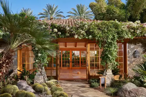 Desert plants surround yoga pavilion building with palm trees at Sensei Porcupine Creek in California