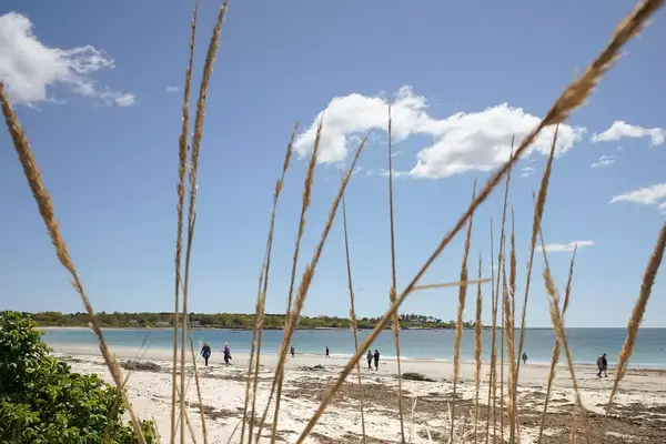 A small number of people walk along the beach at Crescent Beach State Park in Cape Elizabeth