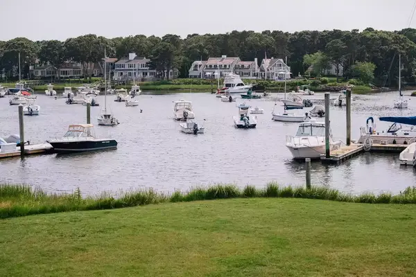A waterfront view with docked boats and houses in the background