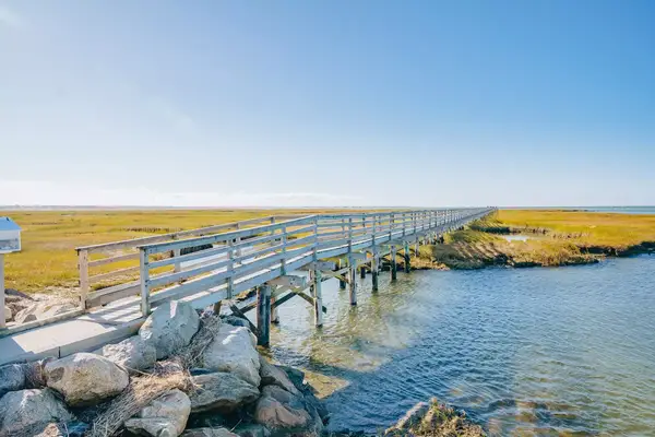 A boardwalk extending over a marsh and water, leading towards the horizon