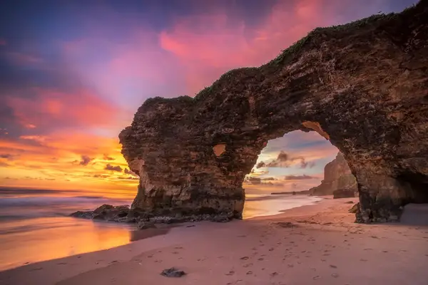 Sunset view with a natural rock arch on a beach