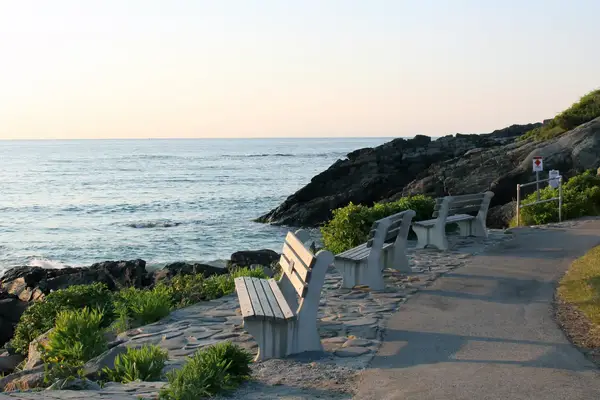 A coastal pathway with benches overlooks the ocean