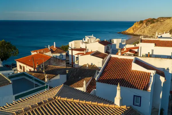Coastal village buildings overlooking the ocean and beach with a cliff in the background