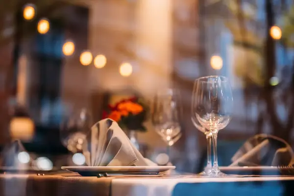 Elegant dining table setup with napkins, plates, and glasses, atmospheric bokeh lighting in the background