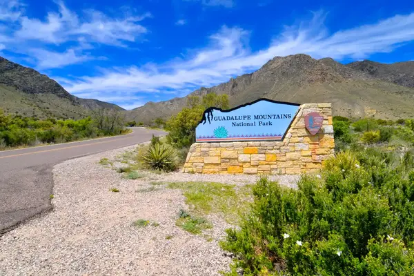 Entrance sign for Guadalupe Mountains National Park on a sunny day, with mountains in the background