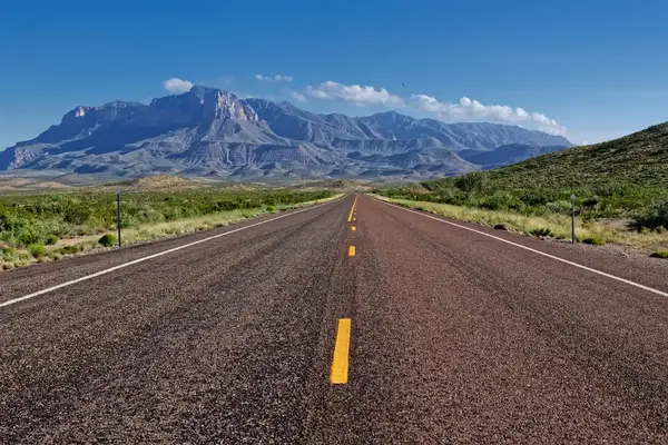 A straight paved road leading towards mountains in the distance