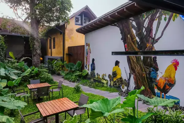 A photo of a courtyard with dining tables and a colorful wall mural