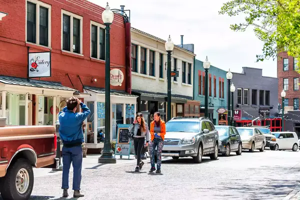 People tourists taking picture on wall street cobblestone road with stores shops
