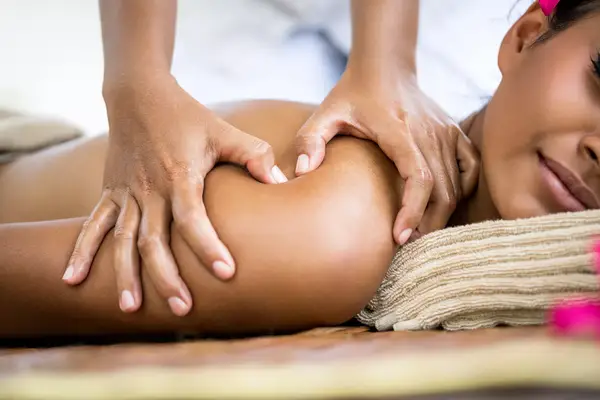Close-up shot of a woman having a Balinese massage with hands on pressure points near her shoulder