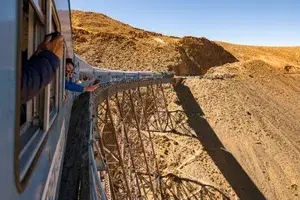 Guests take photos from the windows of the Tren a las Nubes in Argentina as it traverses an elevated track