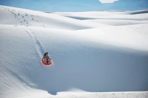 Person sledding on sand dunes at a national park