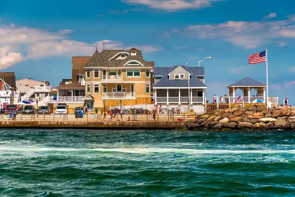 Coastal homes and a gazebo near a rocky shore with a view of the water and an American flag waving