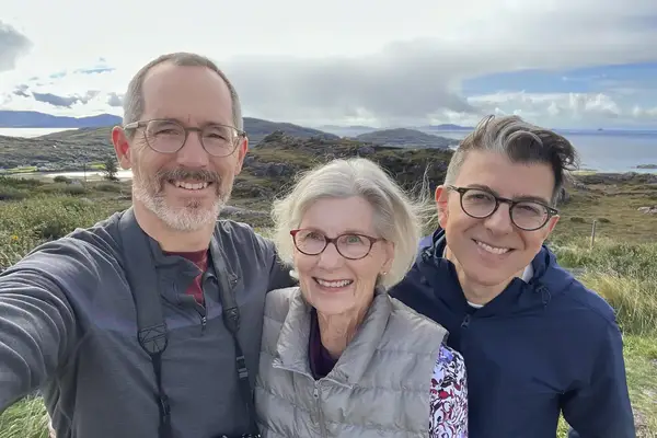 Three people outdoors taking a selfie in a scenic mountainous area