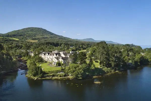 A scenic view of Sheen Falls Lodge surrounded by trees water and hills