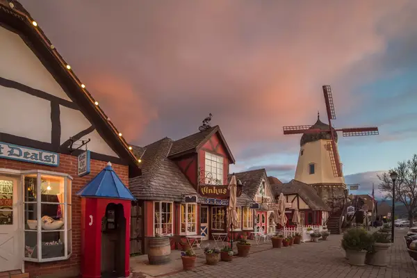european styled store fronts with a tall windmill in the distance at sunset