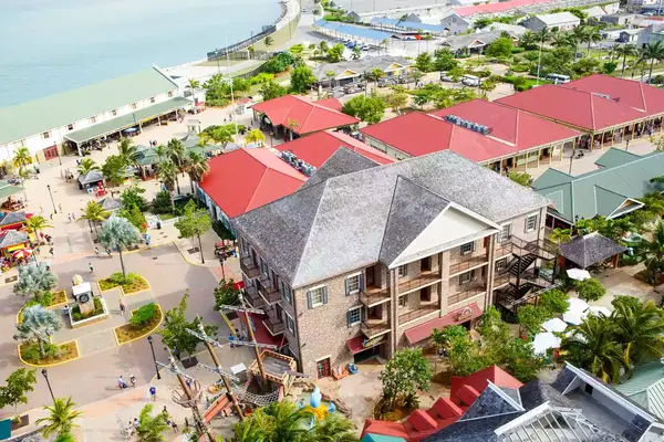 An aerial view of a coastal town square with multiple buildings featuring red roofs and nearby streets