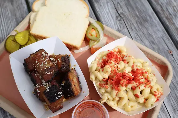 BBQ platter with burnt ends, macaroni and cheese, pickles, white bread, and sauce