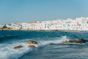 View of the coastline of Paros, Greece, with waves and white housing structures in the background
